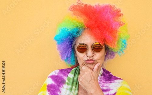 Funny senior woman wearing colorful wig and sunglasses - Joyful elderly lifestyle and party concept