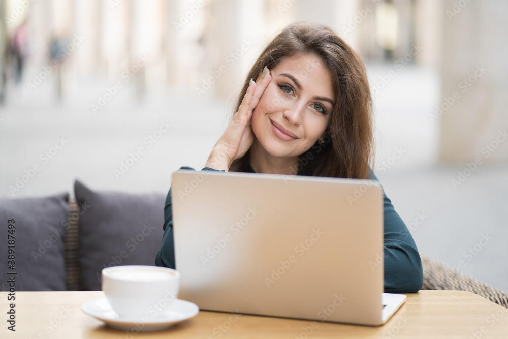 Fototapeta premium teacher teacher at the Institute working on documents report folder on a new laptop computer. professional Manager businesswoman woman brunette long hair in a new dress in a cafe