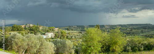 thunderstorm casts dramatic evening light on hilly green landscape, San Gimignano, Siena, Italy