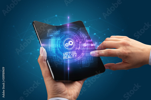 Businessman holding a foldable smartphone with BLOCKCHAIN inscription, new technology concept VIRTUAL REALITY