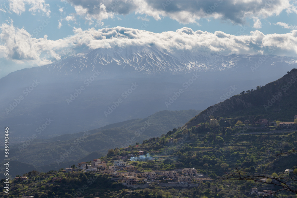 Taormina - The Mt. Etna volcano in the clouds over the Sicilian landscape.
