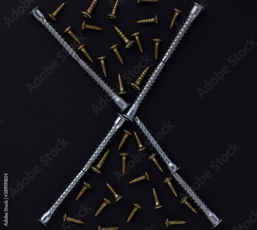 The abstract form and background for the text is made of self-tapping screws and furniture screws on a black background (top view).
