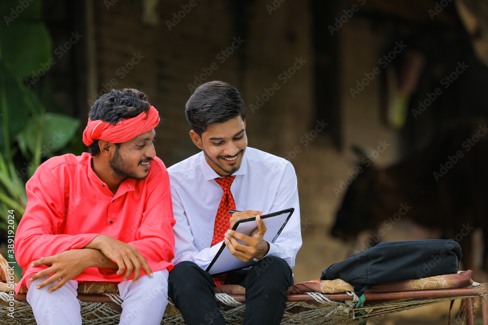 Young indian banker collection information to farmer at home Young indian banker collection information to farmer at home