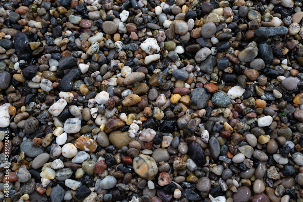 Wet colorful pebbles on the sea beach close up, background texture Wet colorful pebbles on the sea beach close up, background texture