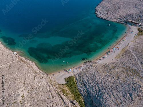 Aerial view of Rucica beach on Pag island, Metajna, Croatia. Seabed and beach seen from above, bathers, relaxation and summer holidays. Promontories and cliffs of Croatian coasts