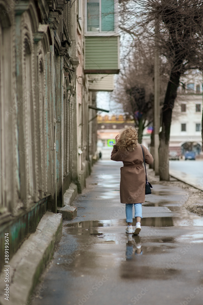 A beautiful young woman runs down the street after the rain. Back girl A beautiful young woman runs down the street after the rain. Back girl