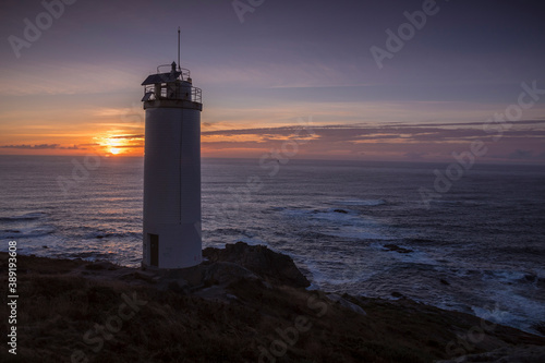 white lighthouse of corme with a beautiful sunset in the background. Lighthouse trail