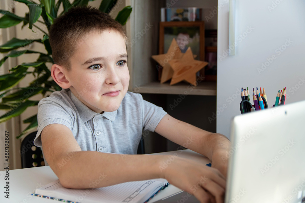 Distance learning online education. A schoolboy is studying at a computer at home and doing school homework. quarantine coronavirus. Distance learning online education. A schoolboy is studying at a computer at home and doing school homework. quarantine coronavirus.