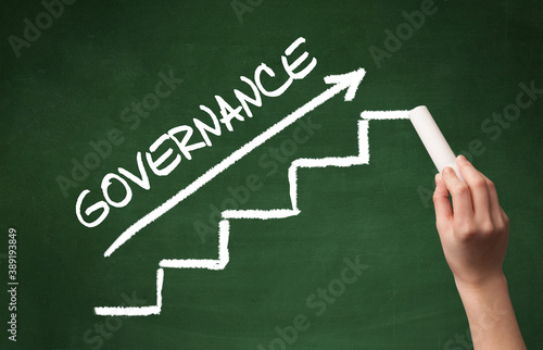 Hand drawing GOVERNANCE inscription with white chalk on blackboard, business concept