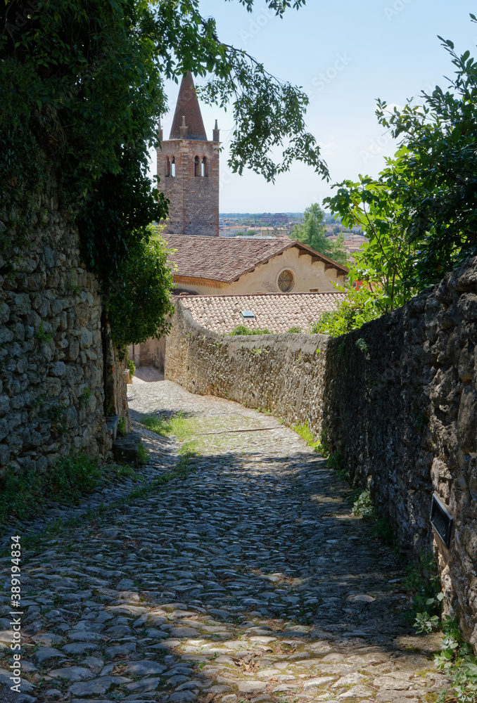 Cobblestone footpath leading from the castle to downtown in Soave, Italy, with the church of Santa Maria of the Dominican Fathers in the background