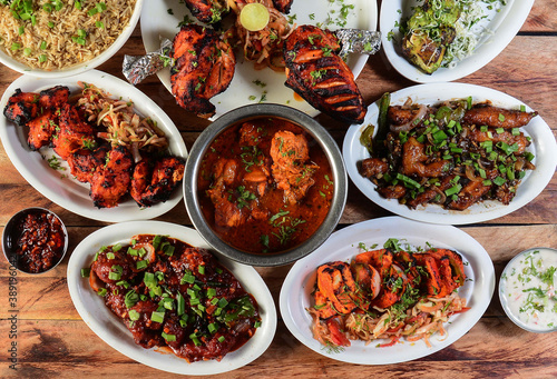 Assorted indian foods chicken pahadi kebab,chicken angara kebab,tandoori chicken,pepper chicken, paneer tikka and chicken masala on wooden background. Dishes and appetizers of indian cuisine