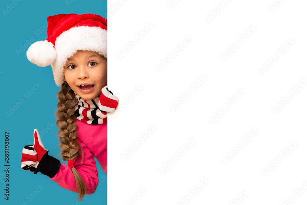 A child looks out from behind a white background on Christmas day. A child looks out from behind a white background on Christmas day.