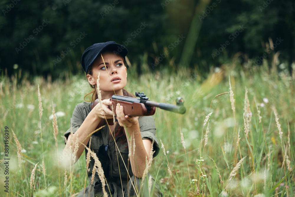Fototapeta premium Woman Holds a weapon in the hands of shelter in the grass fresh air green leaves 