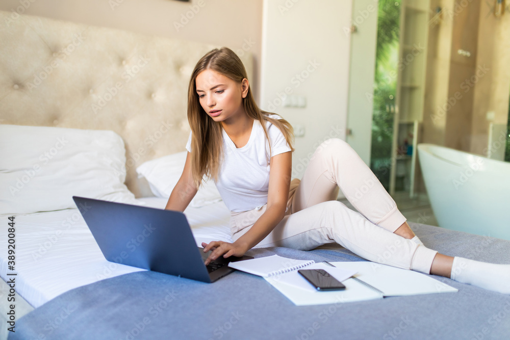 Young successful woman lying on a sofa with laptop paying bills online looking up and thinking Young successful woman lying on a sofa with laptop paying bills online looking up and thinking