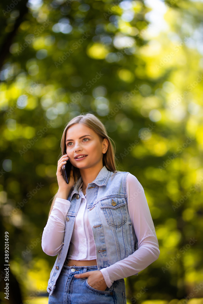 Portrait of a smiling beautiful woman talking on the phone in the park Portrait of a smiling beautiful woman talking on the phone in the park