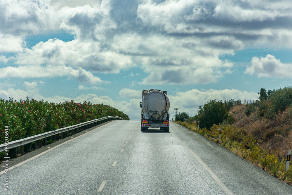 Truck with silo for the transport of powders circulating on the highway on the edge of the horizon with a sky with clouds. Truck with silo for the transport of powders circulating on the highway on the edge of the horizon with a sky with clouds.