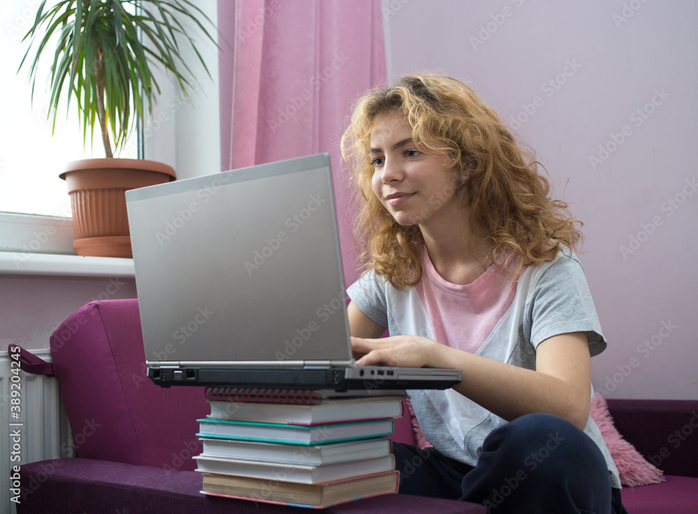 nice girl - teenager of 17 years is preparing for exams at home, sitting on a sofa with a laptop. Home schooling, social networks, distance learning. Knowledge, books, modern digital technologies nice girl - teenager of 17 years is preparing for exams at home, sitting on a sofa with a laptop. Home schooling, social networks, distance learning. Knowledge, books, modern digital technologies