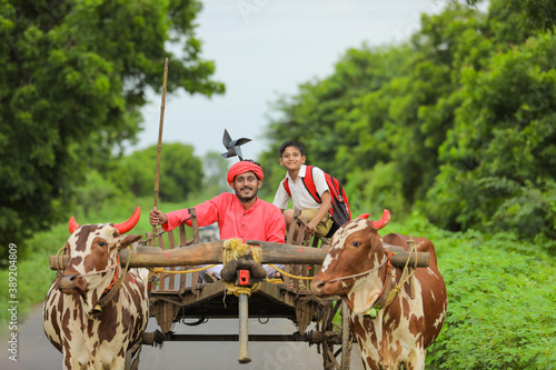Indian farmer and his child on bullock cart