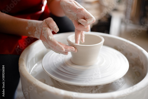 Female hands crafting a pottery cup on a potter's wheel. Handmade and crafting concept.