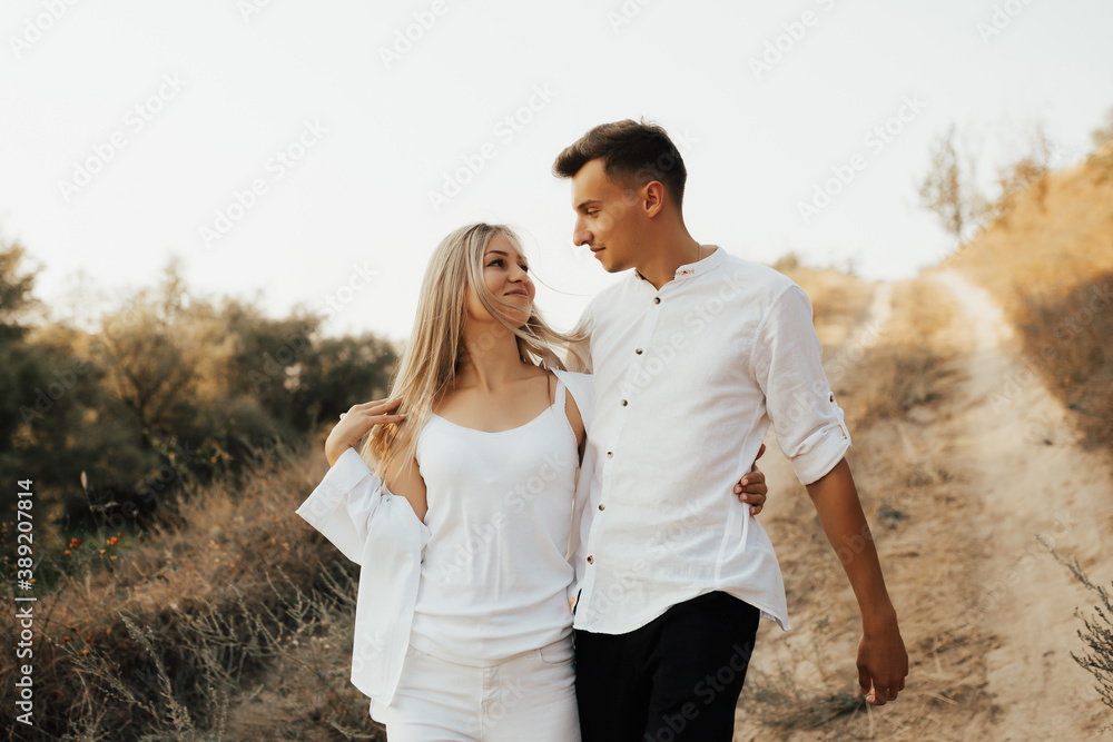 Young couple walking on the country road. They looking each other and smiling.