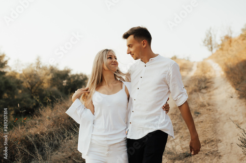 Obraz na płótnie Young couple walking on the country road. They looking each other and smiling. w salonie