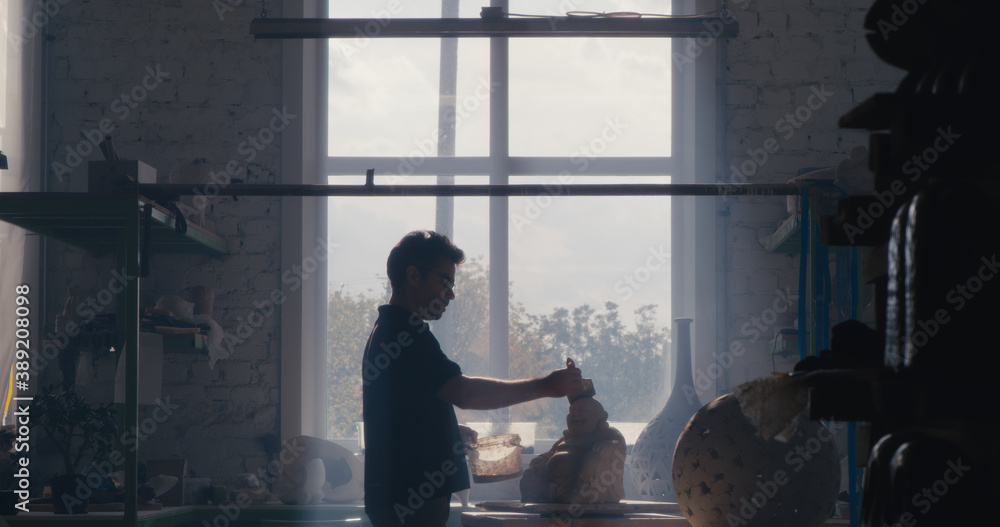 Male artisan working in dark studio Male artisan working in dark studio