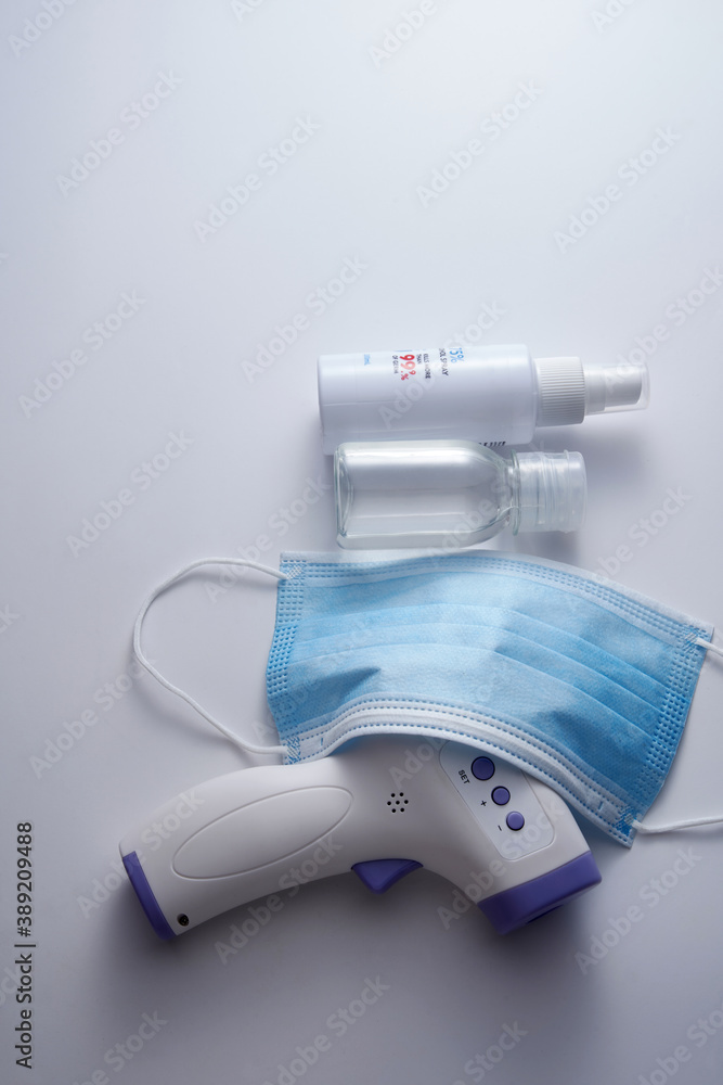 Face mask, bottle with hand sanitizer and thermometer gun on white background. Face mask, bottle with hand sanitizer and thermometer gun on white background.