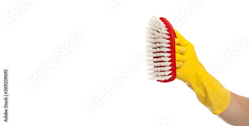 Hand in yellow glove with a red cleaning brush on a white background. Home cleaning concept