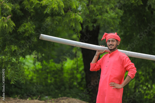 Young indian farmer holding pipe in hand
