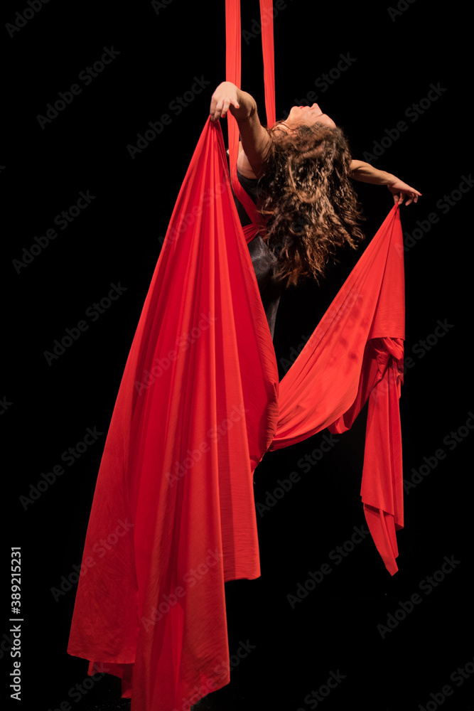 Young woman doing acrobatics on a black background