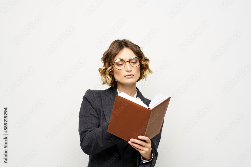 Woman at work with book in hand light background classic suit glasses head Woman at work with book in hand light background classic suit glasses head