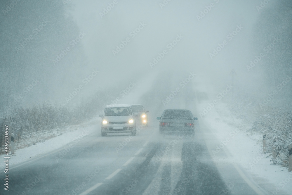 Cars are driving on a winter road in a blizzard Cars are driving on a winter road in a blizzard