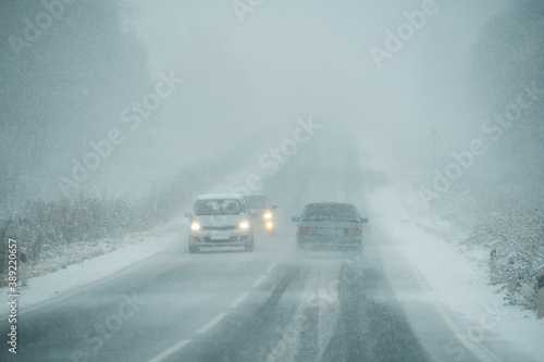 Cars are driving on a winter road in a blizzard 
