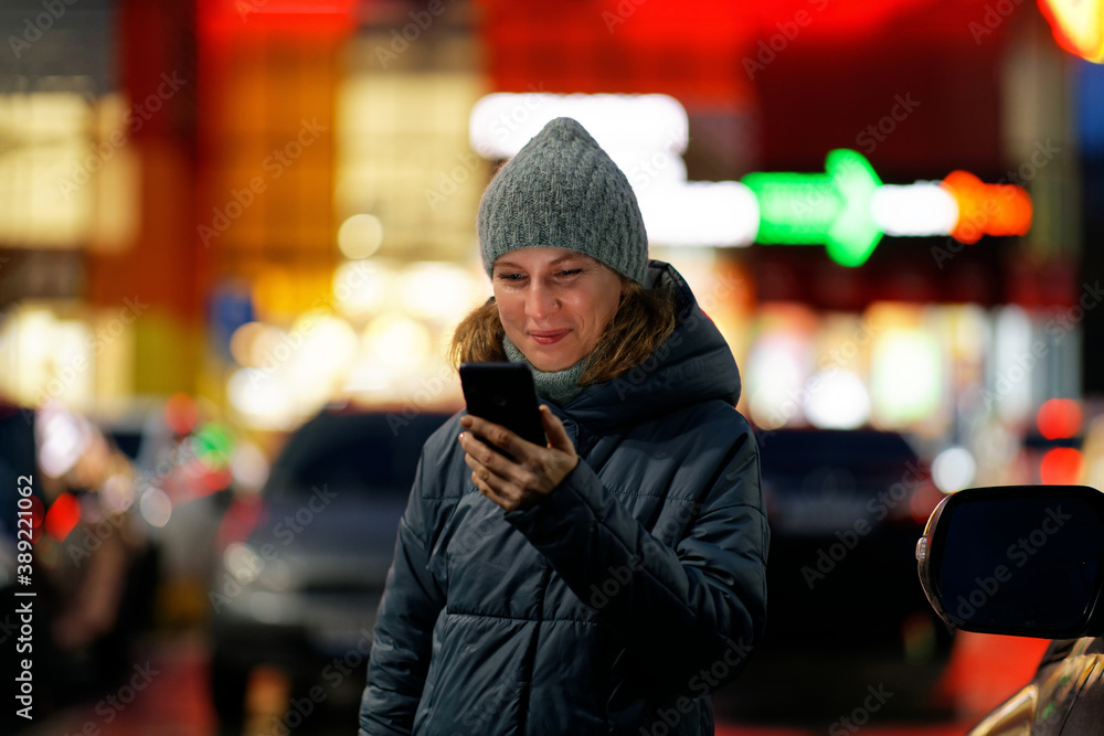 Outdoor portrait of young woman using her smartphone on night city. Shallow focus. Outdoor portrait of young woman using her smartphone on night city. Shallow focus.