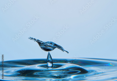 Water drop falling down. Abstract blue background.