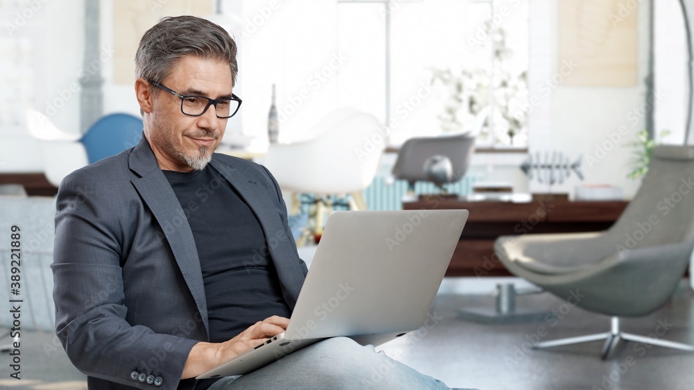 Older man sitting at home in living room working with laptop computer. Business from home in home office. Older man sitting at home in living room working with laptop computer. Business from home in home office.