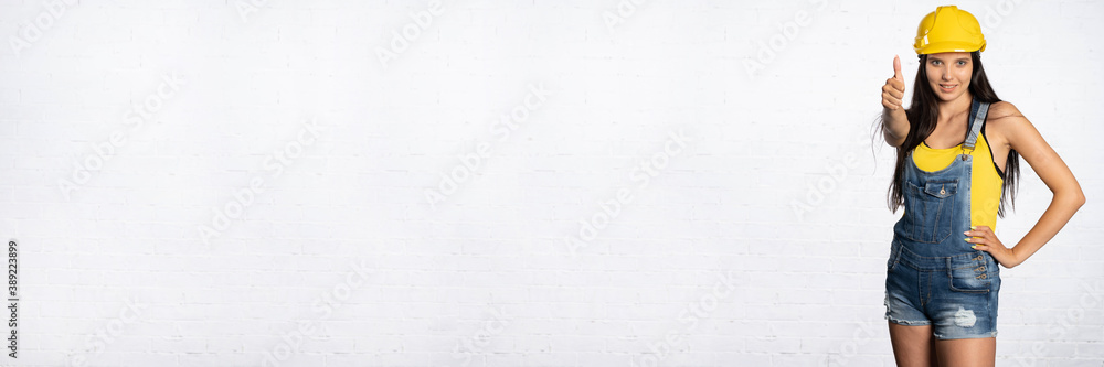 A construction worker shows with her thumb that everything is fine. Positive signs and symbols shown with her hand. A construction worker shows with her thumb that everything is fine. Positive signs and symbols shown with her hand.