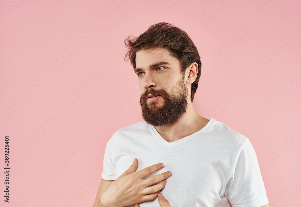 A man with a beard and mustache on a pink background gestures with his hands