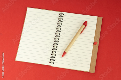 Set of recycle paper notebook and pen. Open diary notebook on red background