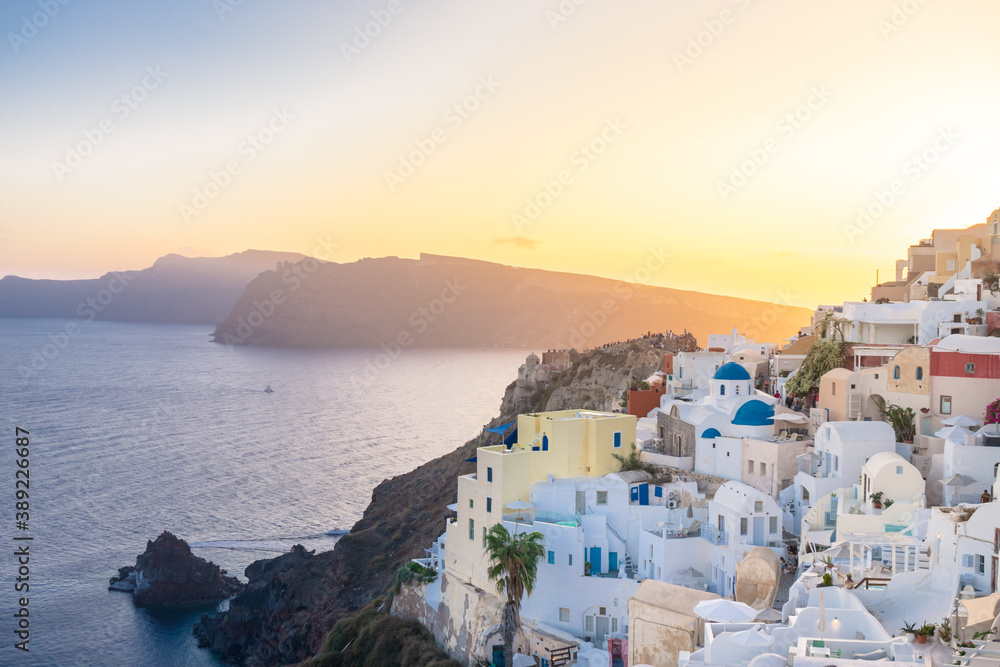 Sunset view of Oia with blue domes, Thirasia in the back, Santorini island, Cyclades, Greece
