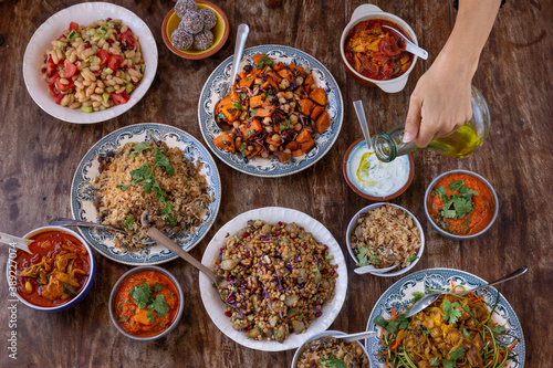 table full of healthy and colorful food with detail of hands touching asian and Mediterranean food