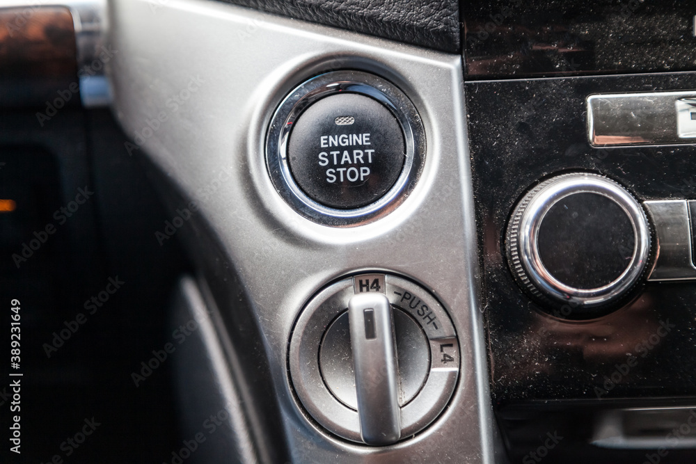 Close-up car engine ignition start and stop button on the dashboard, electric key, modern gray design with chrome elements on the inner panel. Auto service. Close-up car engine ignition start and stop button on the dashboard, electric key, modern gray design with chrome elements on the inner panel. Auto service.