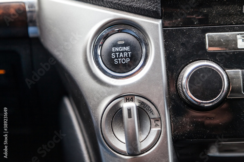 Close-up car engine ignition start and stop button on the dashboard, electric key, modern gray design with chrome elements on the inner panel. Auto service.