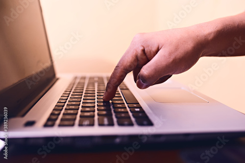 Un dedo presionando una tecla de laptop. 