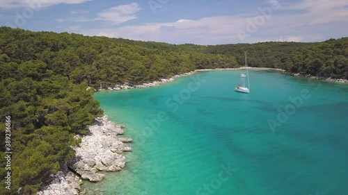 Aerial shot of turquoise water at bay shore, drone flies by luxurious yacht