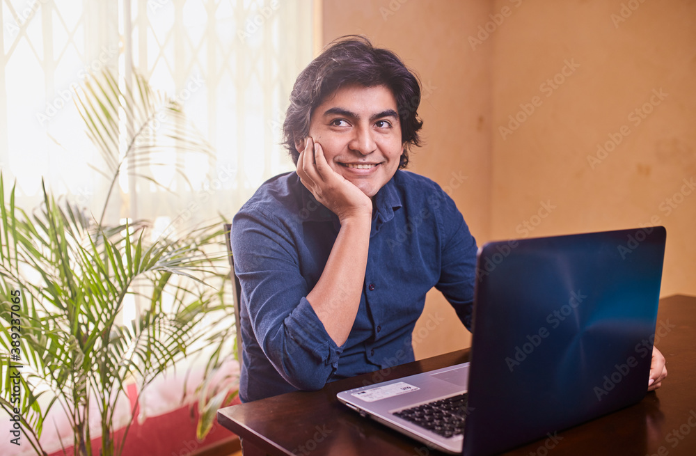 Hombre joven y feliz usando laptop o computadora en escritorio. Teletrabajo desde casa. Oficina en casa. Hombre joven y feliz usando laptop o computadora en escritorio. Teletrabajo desde casa. Oficina en casa.