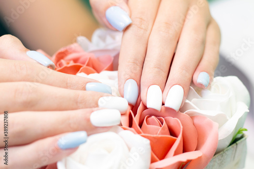 Stylish fashionable female manicure. Beautiful hands of a young woman on a background of flowers and beads from pearls