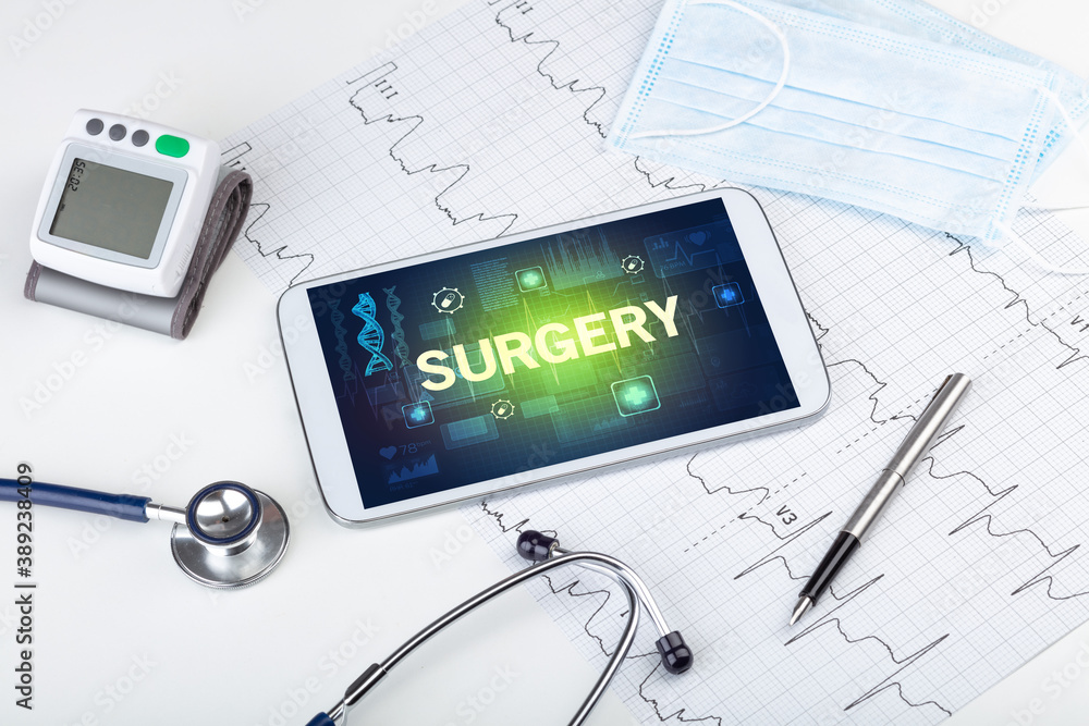 Tablet pc and medical stuff with SURGERY inscription, prevention concept Tablet pc and medical stuff with SURGERY inscription, prevention concept