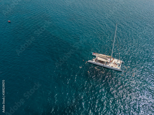 Aerial view of a catamaran with person on board and in the sea swimming, near the coasts of the island of Lanzarote, Canary, Spain. Jet ski performing in the sea  © Naeblys