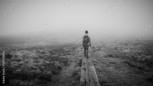 Wicklow way during bad weather, mist and cold. Hiker on wooden path. Mystic atmosphere